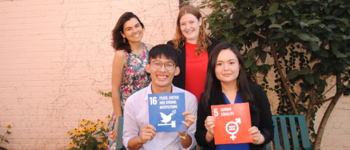 Four students, two of whom are holding SDG signs